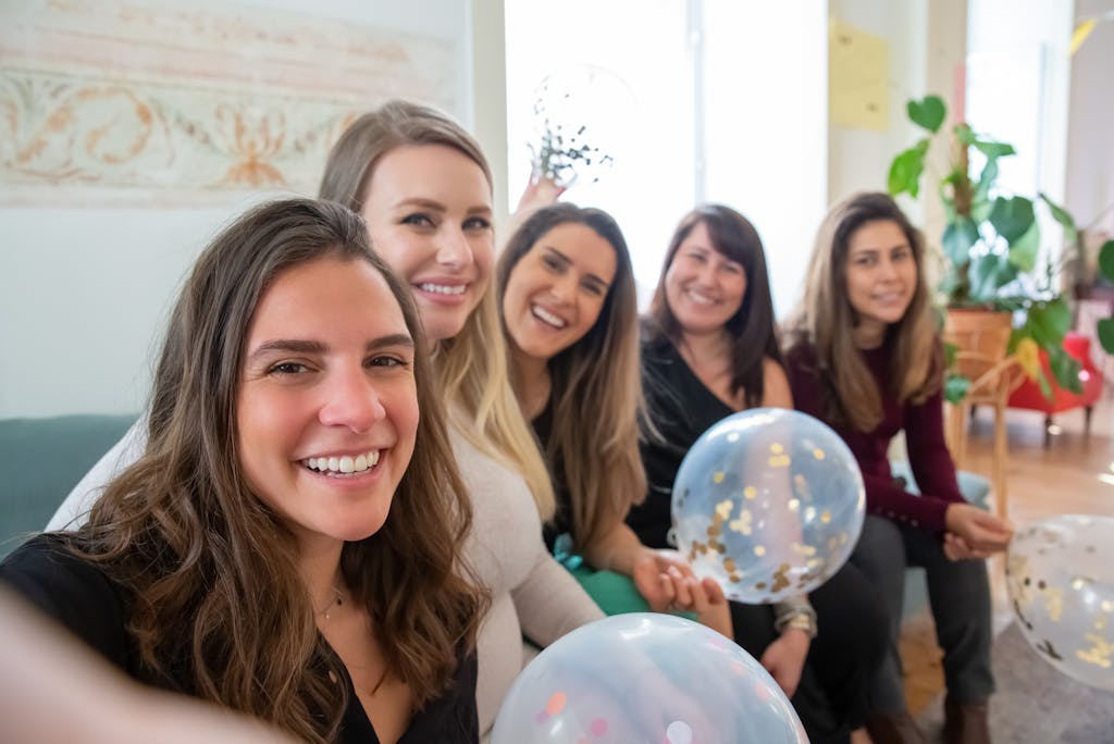Group of women celebrating with balloons indoors, smiling and enjoying the moment.